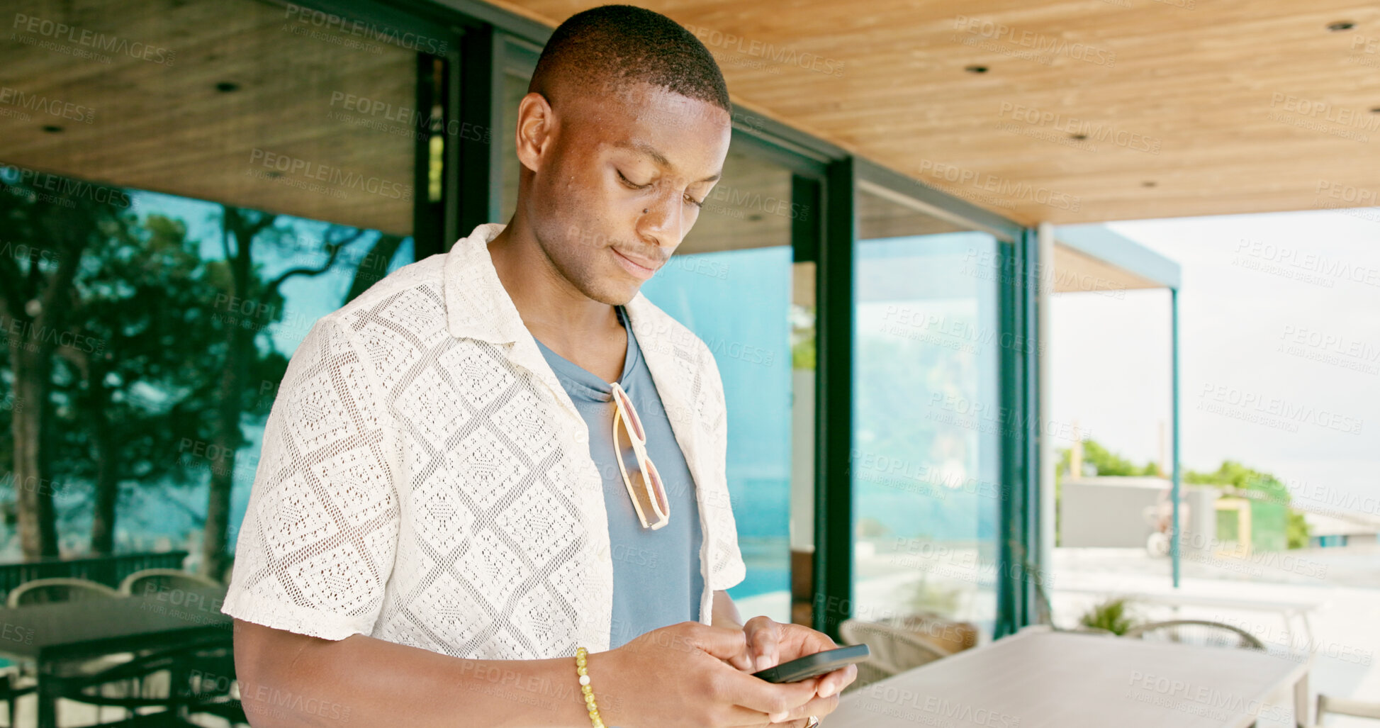 Buy stock photo Black man, typing and outdoor with phone for social media, travel planning and contact at hotel. Person, mobile or scroll at resort for status update, accommodation review or writing blog on platform