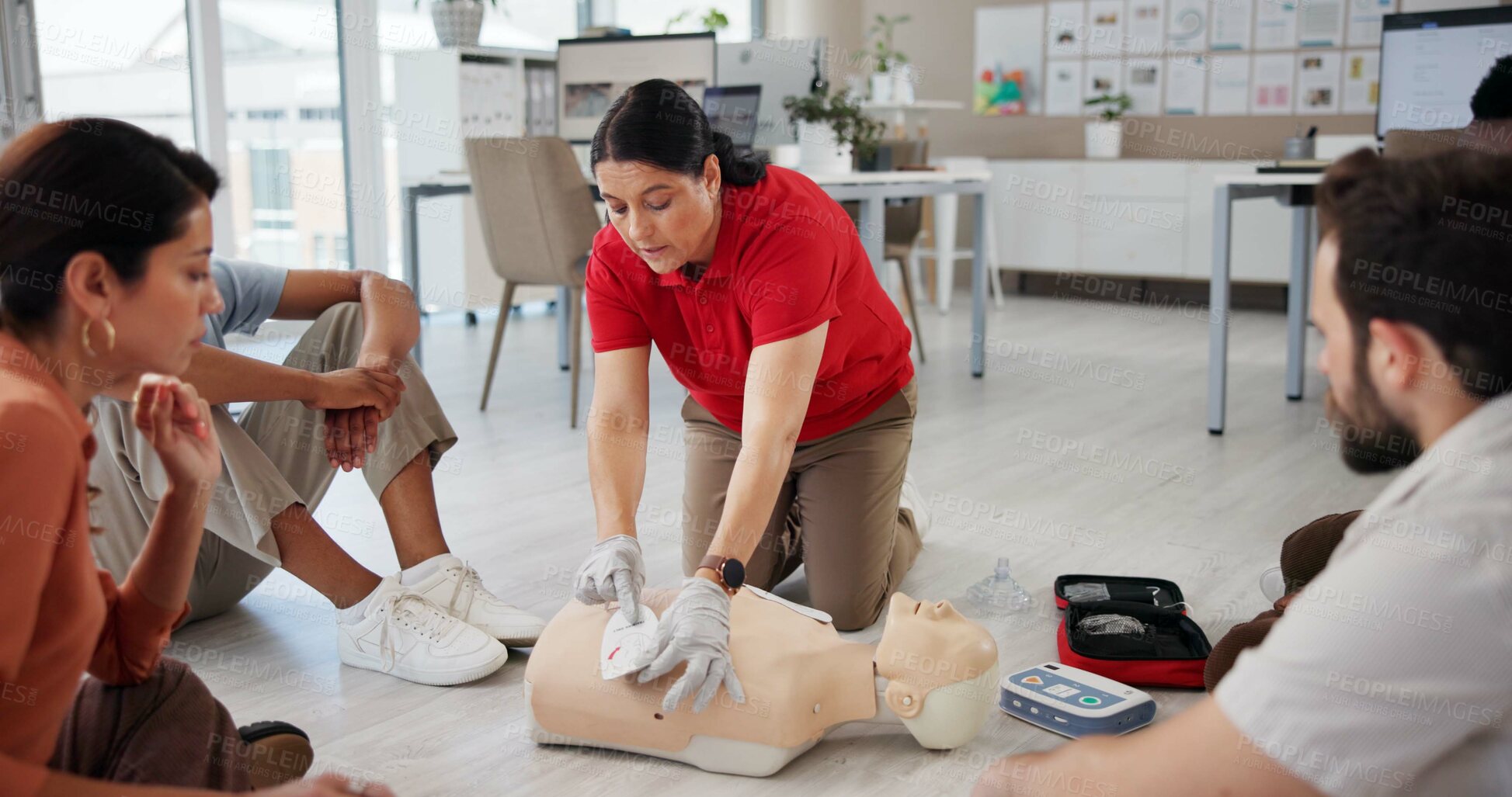 Buy stock photo Mannequin, first aid and workshop with people and defibrillator for teaching, cardiac arrest or safety protocol. Healthcare, medical simulation and heart rhythm rescue with paramedic course in office