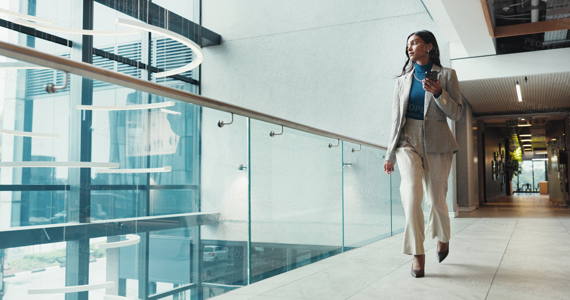 Buy stock photo Corridor, phone and walking with business woman in office for arrival, communication or progress. App, social media and typing text message with Indian employee thinking in corporate workplace