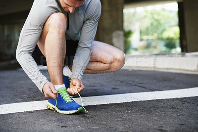 Buy stock photo Cropped shot of a young man tying his laces before a run