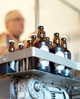 Buy stock photo Shot of a batch of bottled beer in a brewery with an employee in the background