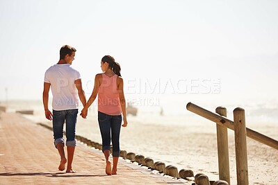 Buy stock photo Man, woman and holding hands for walk by the ocean, back view of romantic date and commitment with trust. Love, care and people outdoor for anniversary, bonding at beach with partner and travel