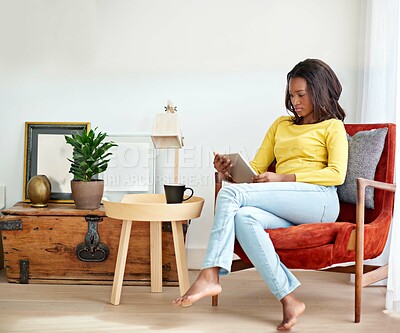 Buy stock photo Cropped shot of an attractive young woman using a digital tablet relaxing at home