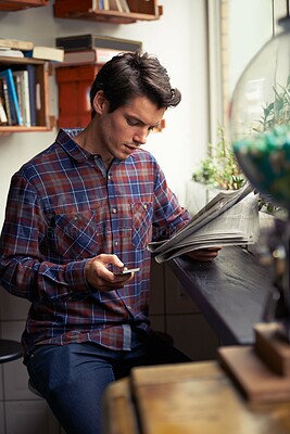Buy stock photo Man, newspaper and phone in cafe, reading and typing for post on social network with story on war. Person, smartphone and scroll on mobile app with contact, article and print media in coffee shop