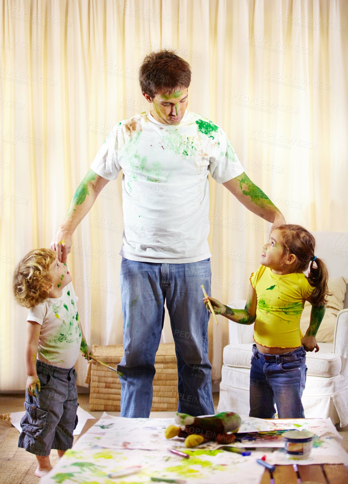 Buy stock photo Shot of a paint covered father scolding his children for making a mess