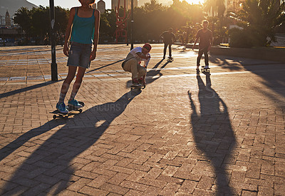 Buy stock photo Friends, skateboard people and sunset in street, city or outdoors for fun practice. Exercise, fitness and group sports with training and skaters bonding together on urban road for downtown workout