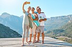 Group of active seniors posing together for a selfie or video call on a sunny day against a mountain view background. Happy diverse retirees taking photo after group yoga session. Living healthy and active lifestyles