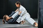 Mma, combat sport and jiu jitsu with two female athletes practicing, training and sparring in fight class. Healthy, fit and active women in gi or uniform learning self defense for safety and health