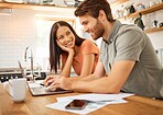 Young cheerful interracial couple bonding while working on a laptop together at home. Caucasian boyfriend and girlfriend working through their bills and using a laptop. Content wife staring at her husband while typing on a computer