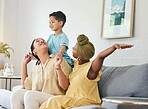 Lesbian couple, gay family and boy child on a sofa with piggyback, game and fun in their home together. Love, lgbt and women mother in a living room with kid and shoulder, hug and playing in a house