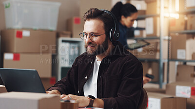 Buy stock photo Man, laptop and headphones with boxes, logistics and typing for inventory, admin and storage at plant. Person, computer and listen to music for shipping schedule, distribution and smile in warehouse