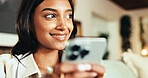Woman, phone and smile with thinking in home, chat and online dating for valentines day in living room. Girl, person and click on app, contact and notification on social media in lounge at apartment