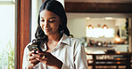 Phone, window and woman in home typing email for hotel booking confirmation with vacation planning. Cellphone, happy and person by glass door with mobile app for holiday house review or feedback.
