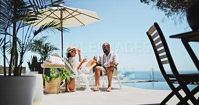 Buy stock photo Couple, relax and champagne on vacation on patio, smile or conversation by ocean, celebration or valentines day. Mature people, man and woman with interracial love, drinks or holiday by sea in summer