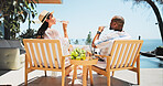 Couple, drinking champagne and vacation on patio, relax and view by ocean, celebration and valentines day. Mature people, man and woman with interracial love, drinks and holiday by sea in summer