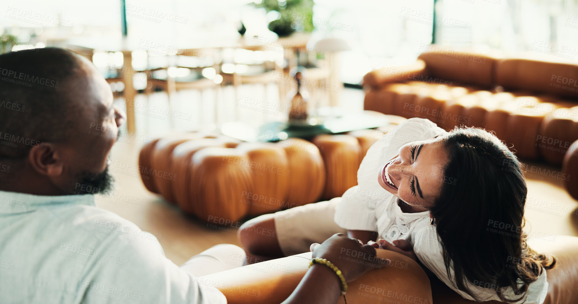 Buy stock photo Laughing, interracial and mature couple in home, relax and listening to joke in living room and comedy. Bonding, man and woman with love in relationship, funny and resting on break and comfortable