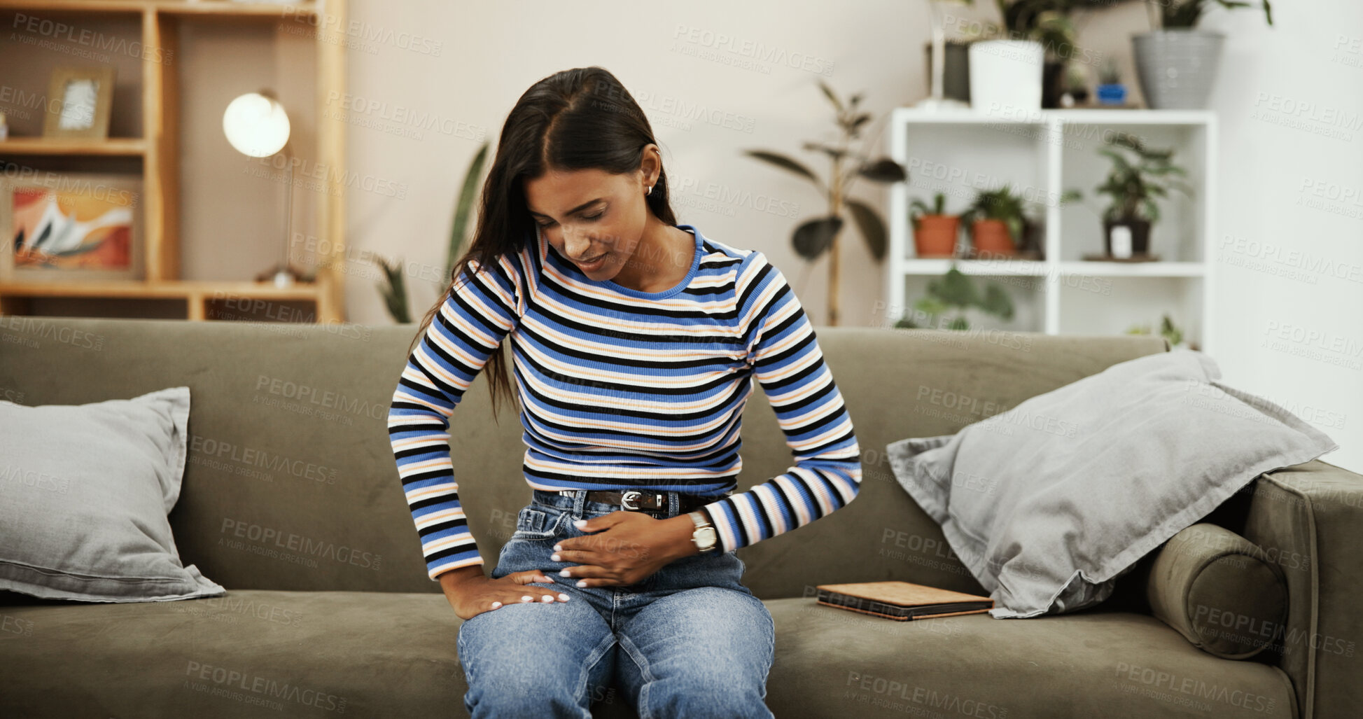Buy stock photo Woman, stomach ache and stress on sofa in home with digestion, virus and sick in living room. Girl, cycle and touch abdomen with bloating, constipation or menstruation on couch in lounge at apartment
