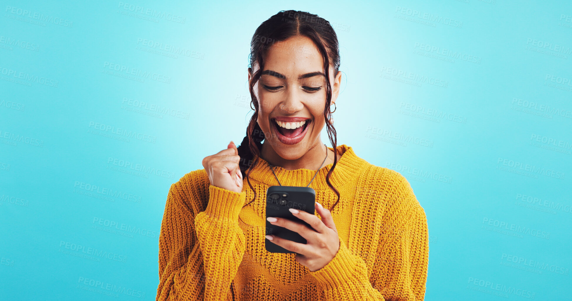 Buy stock photo Woman, celebrate and phone for success in home, lottery winner and online competition achievement. Fist pump, announcement and giveaway opportunity on blue background, election results and reward