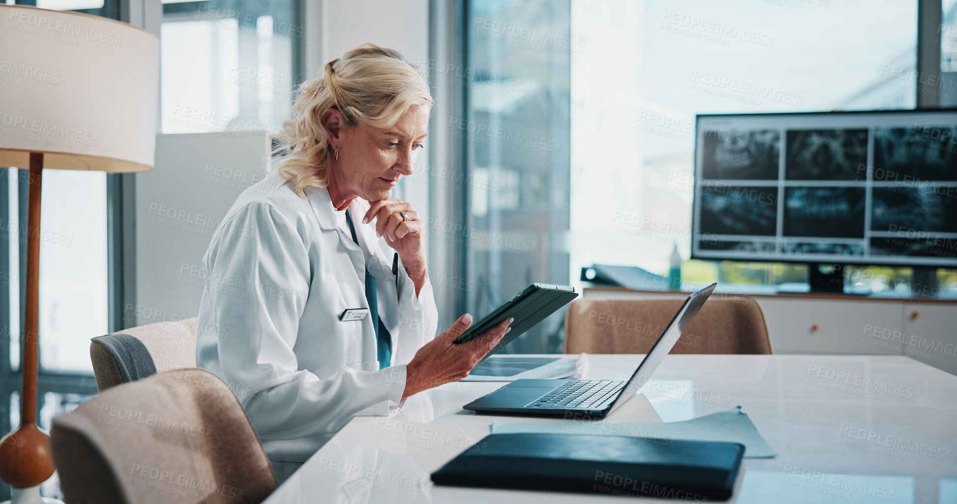 Buy stock photo Doctor, healthcare and technology with woman at office desk in hospital for diagnosis, planning or research. Laptop, tablet and thinking with mature medicine professional in clinic to update records