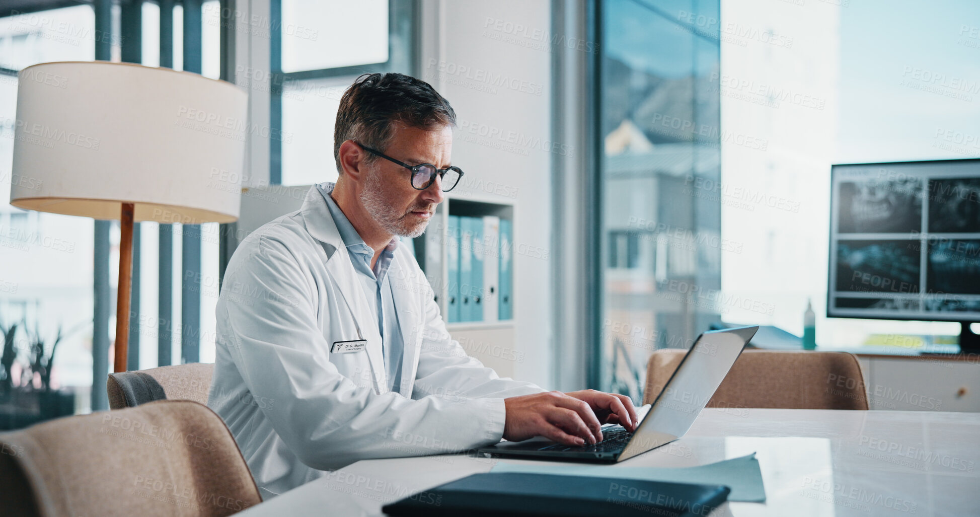 Buy stock photo Doctor, healthcare and laptop with man at desk in office of hospital for diagnosis, planning or research. Computer, medical and typing with mature medicine professional in clinic to update records