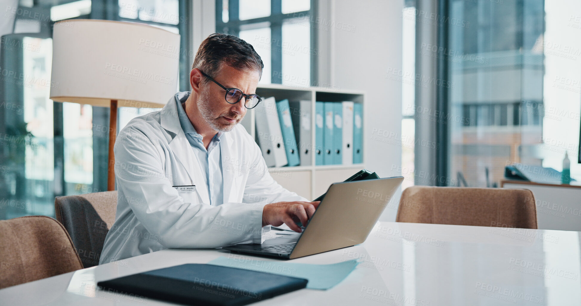 Buy stock photo Healthcare, laptop and report with doctor man at desk in office of hospital for diagnosis, planning or research. Computer, medical and mature medicine professional with pointing or reading in clinic