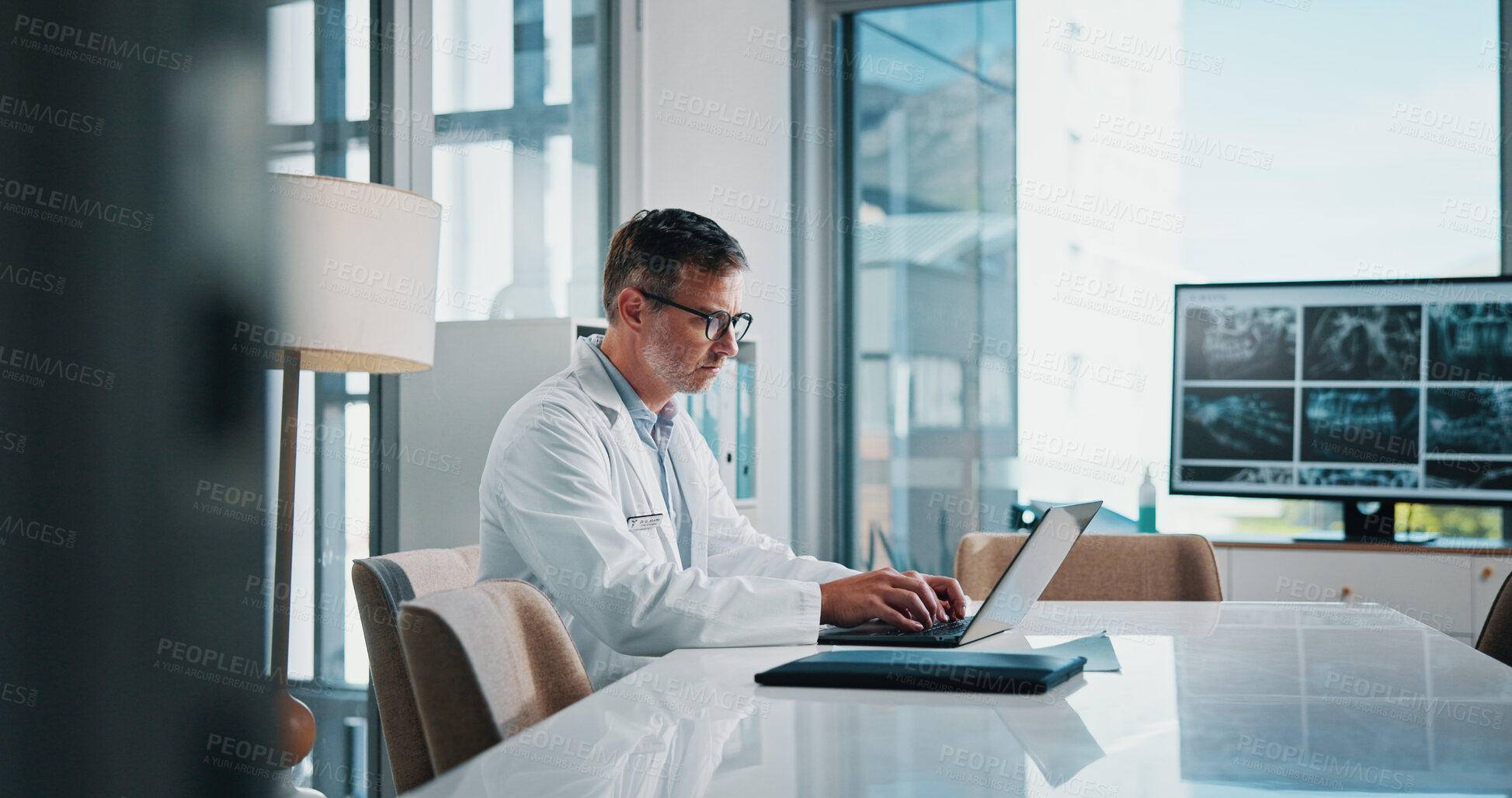 Buy stock photo Doctor, medical and laptop with man at desk in office of hospital for diagnosis, planning or research. Computer, healthcare and xrays with mature medicine professional in clinic to update records