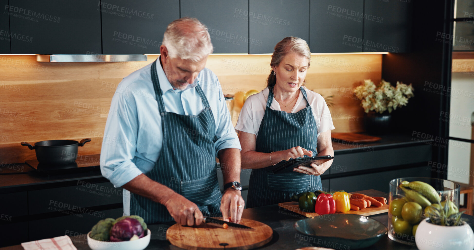 Buy stock photo Mature couple, cooking and recipe on tablet, kitchen and bonding with ingredients for cuisine in home. Healthy food, helping and people with app for research of tips, culinary skills and preparation