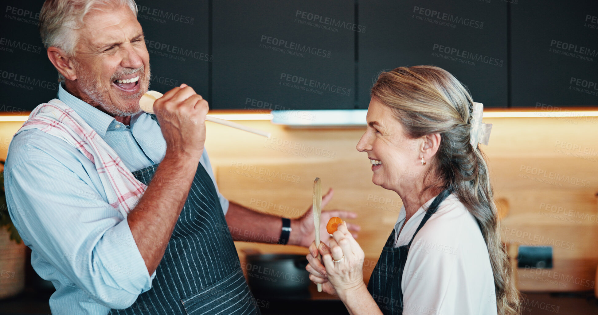 Buy stock photo Singing, cooking and couple together in kitchen for karaoke, retirement celebration or excited for love in home. Senior man, woman or song for music, romance or prepare healthy food with wooden spoon