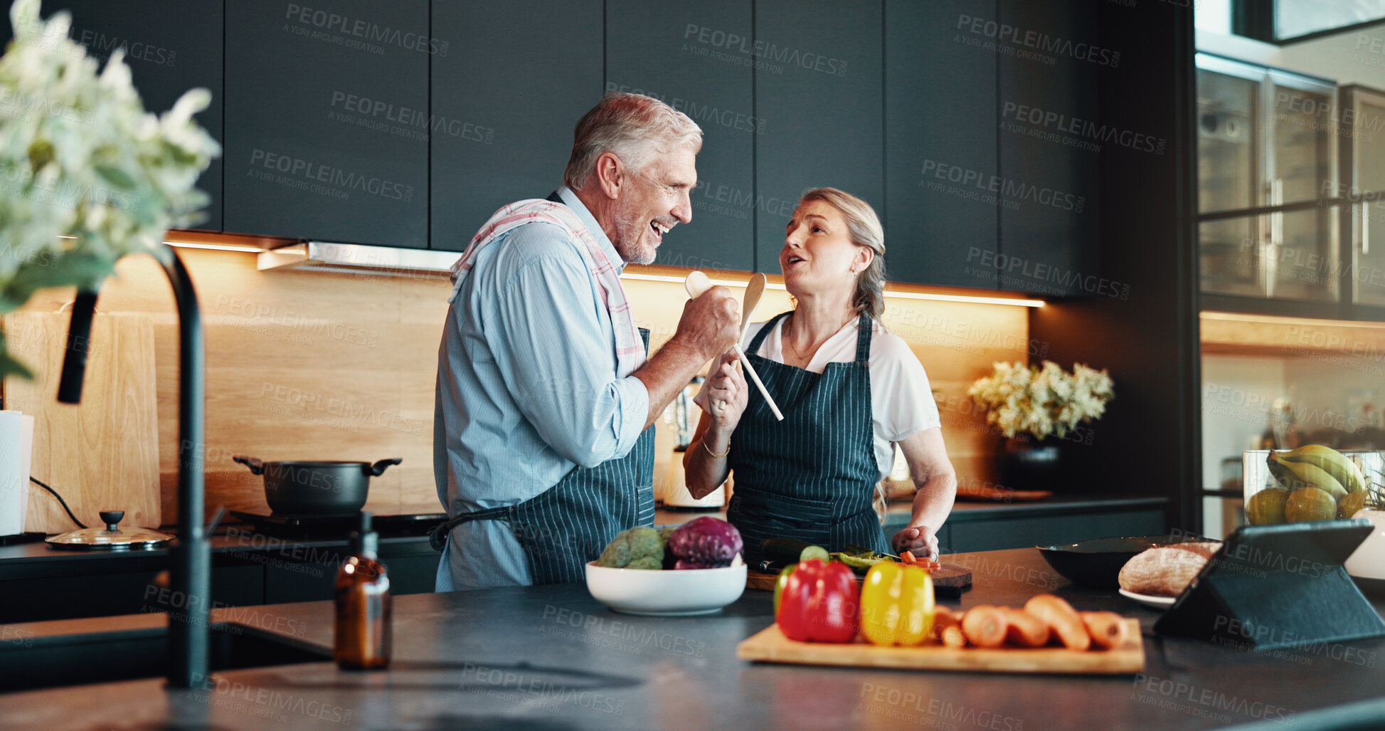 Buy stock photo Singing, cooking and happy couple in kitchen for music, retirement celebration or excited for love in home. Senior man, woman or song for romance, karaoke and prepare healthy food with wooden spoon