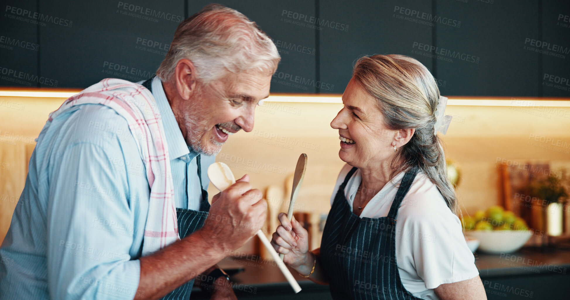 Buy stock photo Singing, cooking and happy senior couple in kitchen for music, retirement celebration and excited for love. Man, woman and song for romance in home, playful karaoke and fun moment with wooden spoon