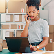 Laptop, shipping and phone call with woman in warehouse for delivery ...