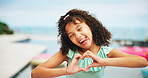 Portrait, heart hands and outdoor with girl, funny face and swimming pool with vacation. Summer holiday, kid and child with gesture for love, romance and kindness with trust, support and happiness
