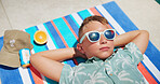 Tanning, sunglasses and boy on towel for outdoor holiday, travel and outdoor vacation to relax. Above, summer and male kid sunbathing in water at lodge, hotel and resort on weekend break in Miami