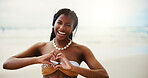 Happy, black woman and portrait with heart hands on beach for summer vacation, love or support in nature. Face, female person or tourist with smile, emoji or shape for holiday on ocean coast at sea