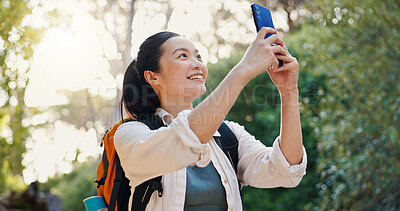 Buy stock photo Adventure, picture and happy woman hiking in nature for natural environment, training and travel. Smile, live streaming and hiker taking photograph in forest for social media, trekking or camping