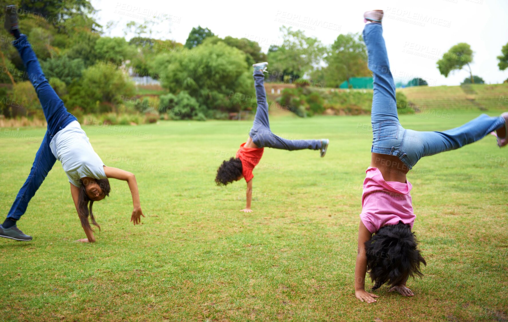 Buy stock photo Three young children doing handstands in the park