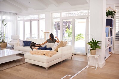 Buy stock photo A young woman sitting on the couch in her home