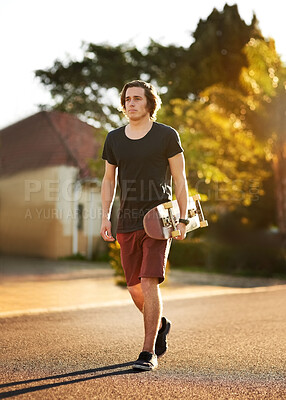 Buy stock photo Skateboard, outdoor and young man walking in street for skating, hobby or skill training in neighbourhood. Skater, confident and teenager for extreme sports, balance or recreation activity on weekend