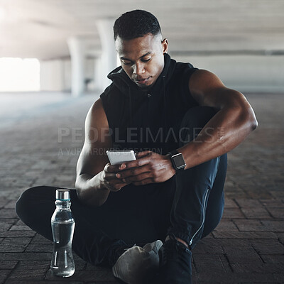 Buy stock photo Black man, phone and break from exercise in city with texting, reading or relax on ground with fitness. Male person, smartphone and runner with contact, app or social media on concrete in New York