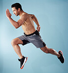 Fullbody young hispanic man running in studio isolated against a blue background. Mixed race shirtless male athlete running or sprinting to win a race. Endurance training to increase his cardio