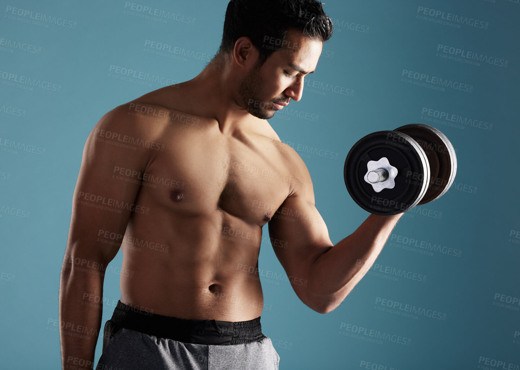 Buy stock photo Fitness, studio and man training with dumbbell for workout, exercise and growth for health. Muscle, shirtless bodybuilder and weightlifting for bicep strength, power and energy on blue background