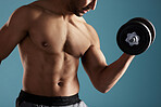 Closeup young hispanic man training with dumbbells in studio isolated against a blue background. Mixed race shirtless male athlete exercising or working out to increase his strength and fitness