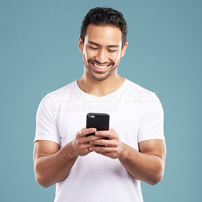 Buy stock photo Studio, man and smile with smartphone for chat, online communication and flirting on dating website. Blue background, male person and happy with mobile for app, reel comment and text on social media