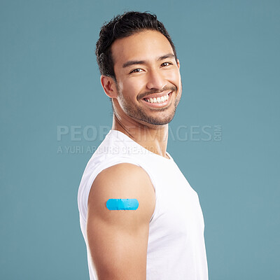 Buy stock photo Studio, happy man and portrait with plaster for medicine, injection wound and safety for Influenza. Blue background, male person and smile with bandage for healthcare, vaccine and treatment for virus