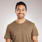 Handsome young mixed race man smiling and happy while standing in studio isolated against a grey background. Hispanic male in casual wear expressing happiness with a smile and looking at the camera