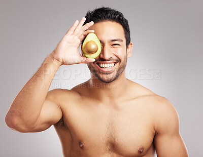 Buy stock photo Avocado, beauty and laughing with man in studio for natural cosmetics or dermatology routine. Aesthetic, detox and skincare with funny shirtless model on gray background for organic cosmetology