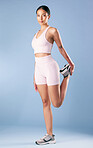 Mixed race fitness woman stretching in studio against a blue background. Beautiful young hispanic female athlete warming up for exercising or working out. Dedicated to a fit and healthy lifestyle