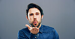 Man, portrait and blowing with kiss for affection, love or romance on a gray studio background. Male person, face or handsome model with hand or romantic gesture for distant compassion on space