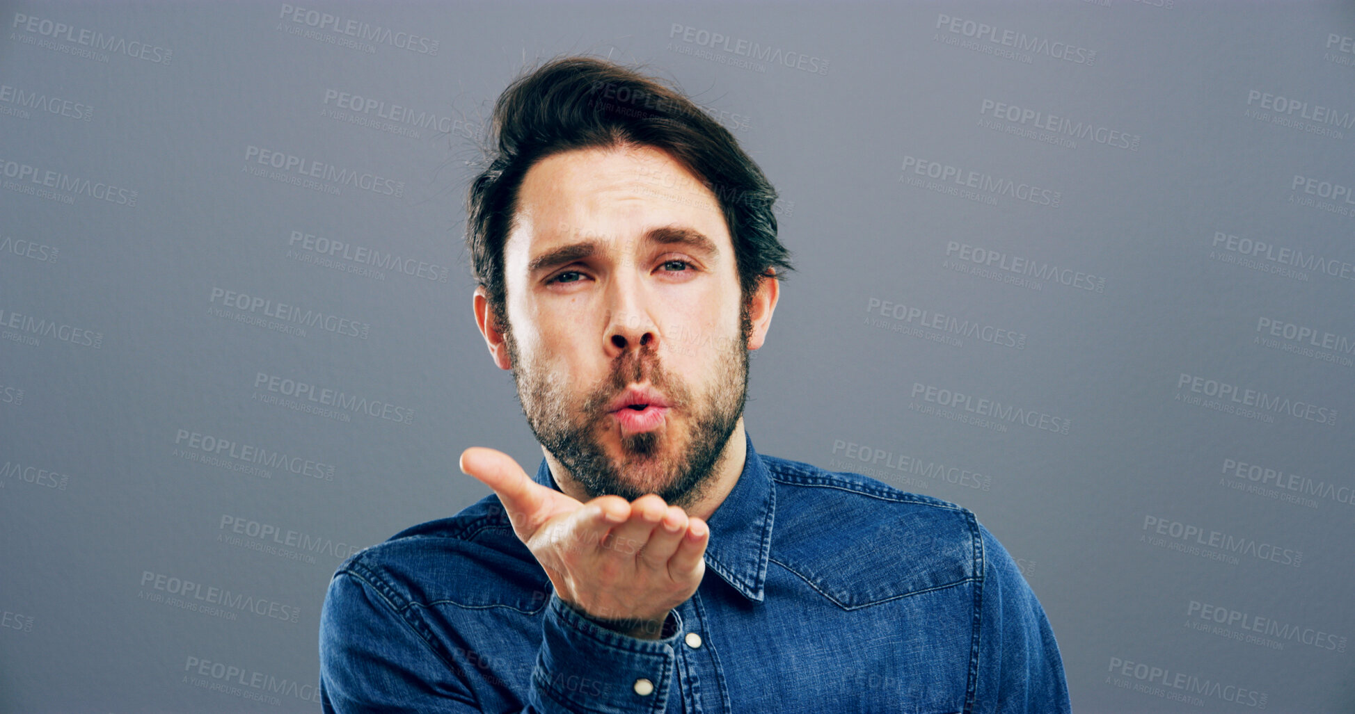 Buy stock photo Man, portrait and blowing with kiss for affection, love or romance on a gray studio background. Male person, face or model with hand, romantic gesture or expression for distant compassion on space