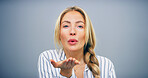 Blowing kiss, studio and portrait of woman with reaction for flirting, romance and affection on blue background. Happy, hand gesture and isolated person with emoji for love, dating and valentines day